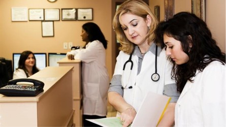 Several healthcare workers looking at paperwork or talking in a healthcare office.