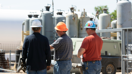 Three workers at worksite discussing the project.