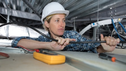 Woman installing electrical wires in small space