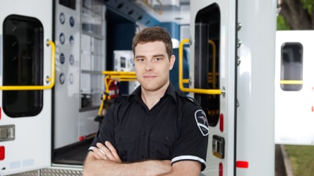 Male first responder posing in front of ambulance
