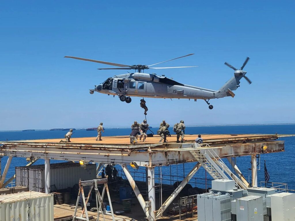 Soldiers deploying from a Navy helicopter.